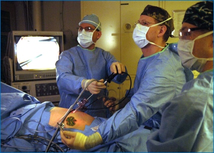 Surgeon performing keyhole bowel cancer operation with an assistant holding the laparoscope