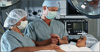 Colorectal surgeon and nurse talking to patient after a laparoscopic colorectal surgery to remove a bowel cancer